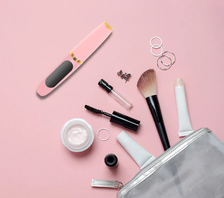 LumaCurl™ lash curler in makeup bag – portable heated eyelash tool with cosmetics on pink background